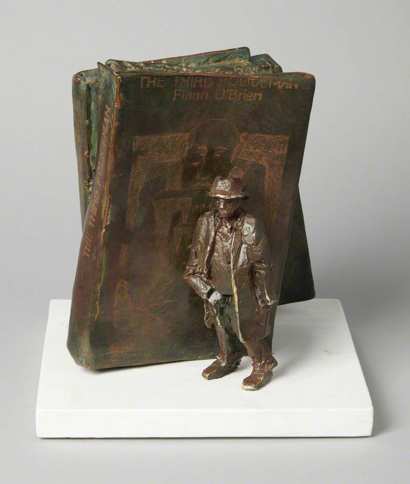 Sculpture of a figure standing beside books